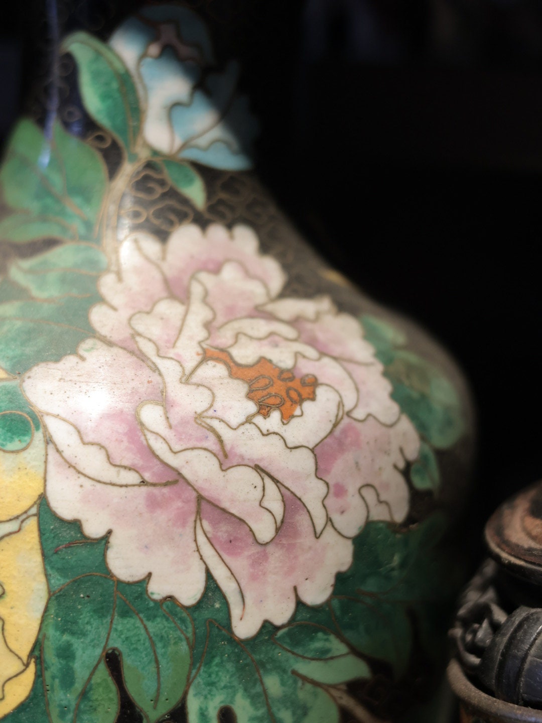 Side view of the vase, with emphasis on the pink and green floral elements, giving a clear view of the enamel craftsmanship.